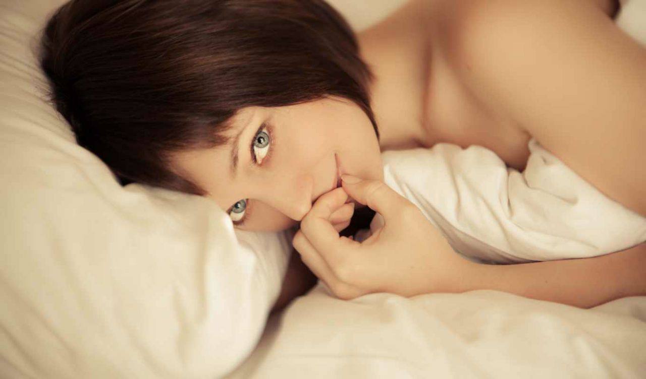 Фото девушки с красивой внешностью нежно ласкающей себя в постели